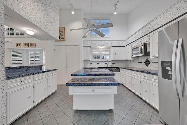 12 E Dansby Dr, Galveston, TX 77551 - kitchen with stainless steel appliances, track lighting, ceiling fan, tile patterned flooring, and a towering ceiling
