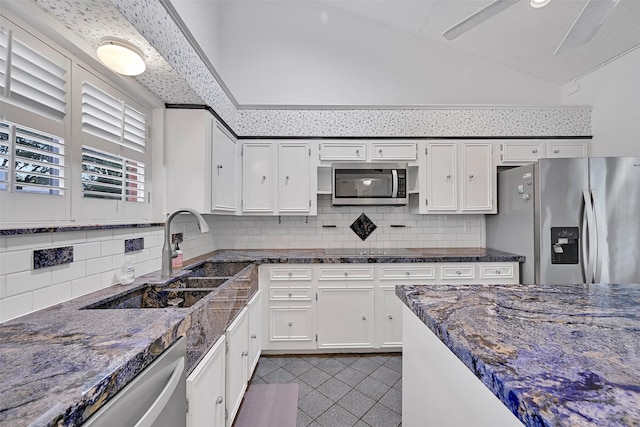 12 E Dansby Dr, Galveston, TX 77551 - kitchen with appliances with stainless steel finishes, dark tile patterned floors, white cabinets, backsplash, and lofted ceiling