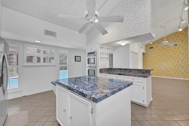 12 E Dansby Dr, Galveston, TX 77551 - kitchen with light tile patterned floors, double oven, wallpapered walls, a ceiling fan, and plenty of natural light