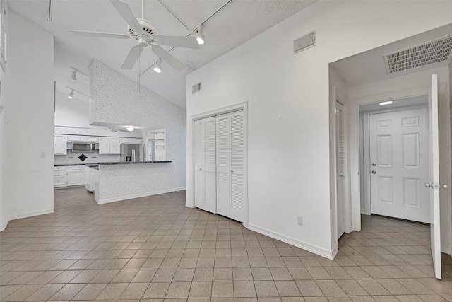 12 E Dansby Dr, Galveston, TX 77551 - unfurnished living room featuring track lighting, high vaulted ceiling, ceiling fan, and light tile patterned floors