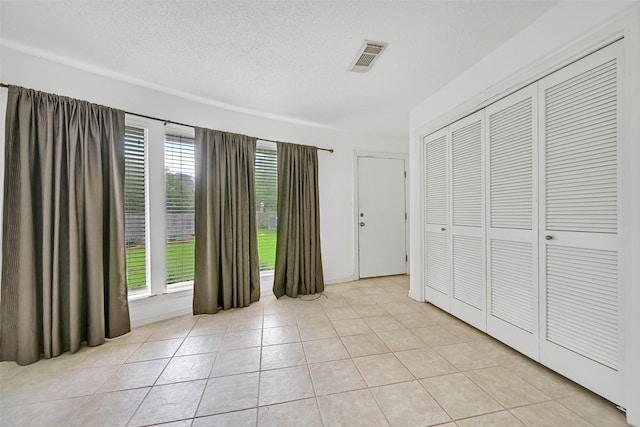 12 E Dansby Dr, Galveston, TX 77551 - unfurnished bedroom with light tile patterned floors, a textured ceiling, and a closet