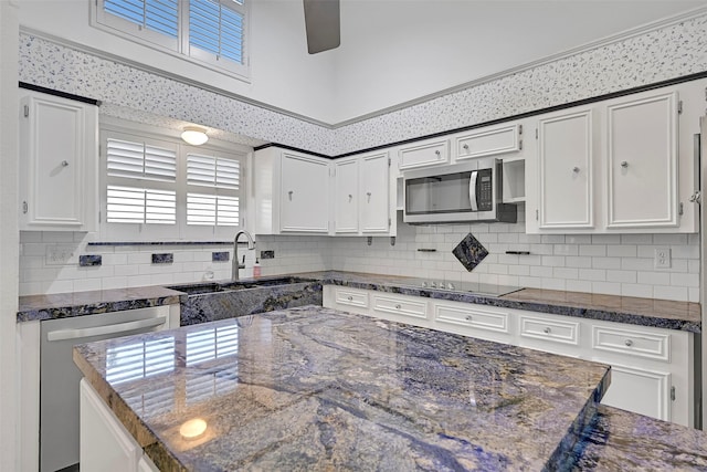 12 E Dansby Dr, Galveston, TX 77551 - kitchen with appliances with stainless steel finishes, white cabinetry, backsplash, and dark stone countertops