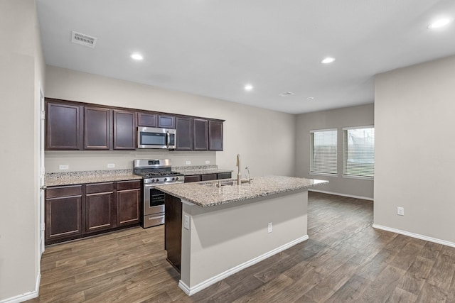 2431 Sutton Hollow Ct, Spring, TX 77373 - kitchen featuring appliances with stainless steel finishes, dark wood-style flooring, dark brown cabinetry, an island with sink, and recessed lighting