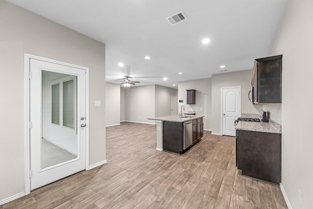 2431 Sutton Hollow Ct, Spring, TX 77373 - kitchen with light wood-style floors, dark brown cabinets, open floor plan, a kitchen island with sink, and recessed lighting