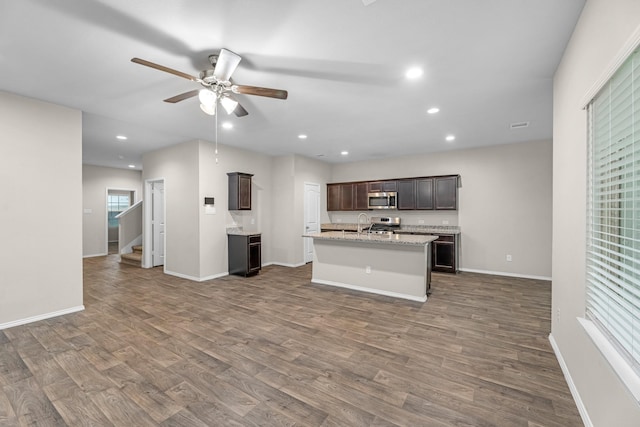 2431 Sutton Hollow Ct, Spring, TX 77373 - kitchen with stainless steel microwave, ceiling fan, dark wood-style flooring, a kitchen island with sink, and dark brown cabinets