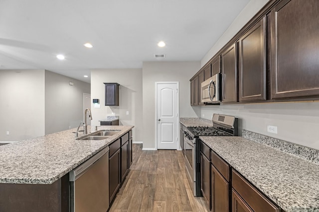 2431 Sutton Hollow Ct, Spring, TX 77373 - kitchen featuring stainless steel appliances, wood finished floors, dark brown cabinetry, light stone counters, and recessed lighting