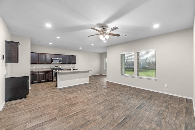 2431 Sutton Hollow Ct, Spring, TX 77373 - kitchen featuring appliances with stainless steel finishes, open floor plan, light wood finished floors, recessed lighting, and a ceiling fan