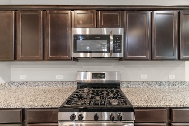 2431 Sutton Hollow Ct, Spring, TX 77373 - kitchen with appliances with stainless steel finishes, dark brown cabinets, and light stone counters