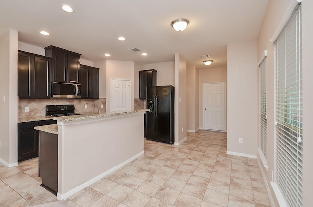 6042 Wesley Manor Ct, Katy, TX 77449 - kitchen with black refrigerator with ice dispenser, stainless steel microwave, range, tasteful backsplash, and light stone countertops
