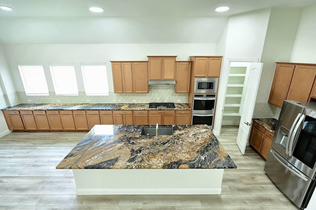 9002 Lacombe Ln, Tomball, TX 77375 - kitchen with appliances with stainless steel finishes, brown cabinetry, tasteful backsplash, light wood finished floors, and recessed lighting