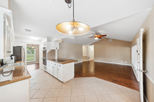 4117 Tilson Ln, Houston, TX 77080 - kitchen with a ceiling fan, light tile patterned floors, black electric stovetop, white cabinetry, and lofted ceiling