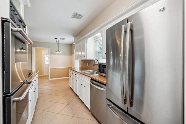 4117 Tilson Ln, Houston, TX 77080 - kitchen featuring stainless steel appliances, white cabinets, light tile patterned floors, and plenty of natural light