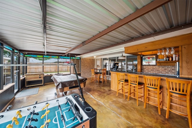 4117 Tilson Ln, Houston, TX 77080 - game room with concrete flooring, a dry bar, brick wall, and plenty of natural light