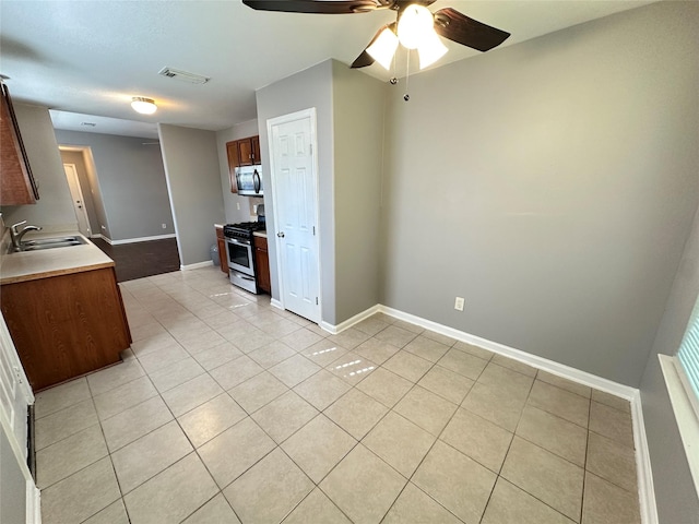 2827 Cypress Island Dr, Houston, TX 77073 - kitchen with stainless steel appliances, light tile patterned flooring, a ceiling fan, and light countertops
