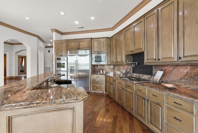 3045 S Island Dr, Seabrook, TX 77586 - kitchen featuring built in appliances, arched walkways, crown molding, recessed lighting, and dark stone countertops