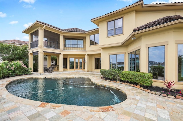3045 S Island Dr, Seabrook, TX 77586 - rear view of house with a balcony, a patio, a tiled roof, stucco siding, and an outdoor pool