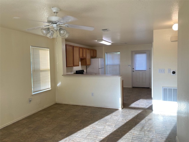 13023 Pleasant Valley Dr, Rosharon, TX 77583 - kitchen featuring freestanding refrigerator, a ceiling fan, brown cabinets, and a peninsula