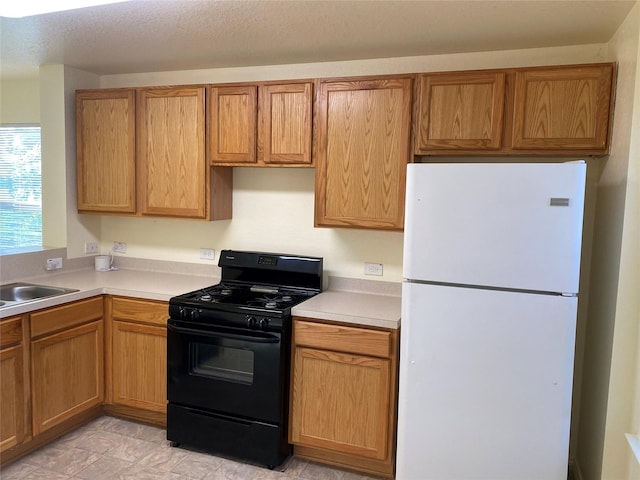 13023 Pleasant Valley Dr, Rosharon, TX 77583 - kitchen with freestanding refrigerator, black gas range, light countertops, and brown cabinetry