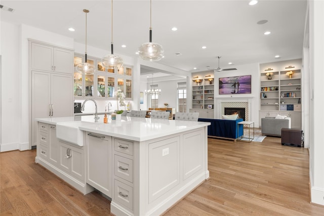 2324 Albans Rd, Houston, TX 77005 - kitchen with a tiled fireplace, a ceiling fan, white cabinetry, a center island with sink, and recessed lighting