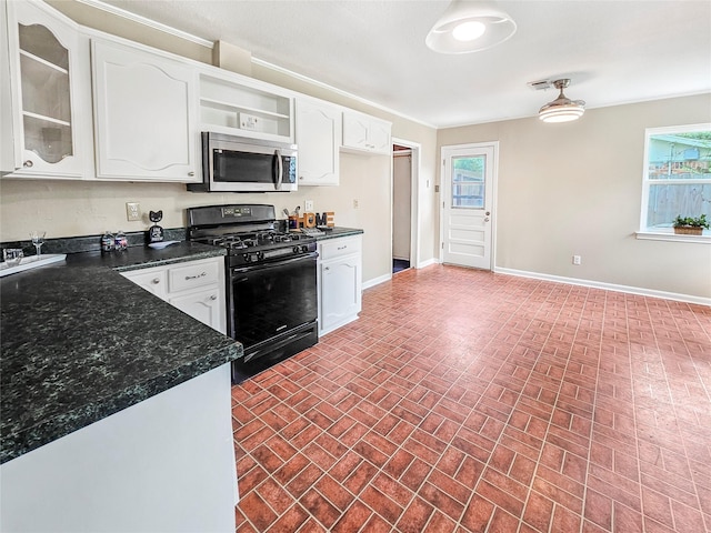 723 Pas Trl, Houston, TX 77336 - kitchen with stainless steel microwave, gas stove, brick patterned flooring, white cabinets, and open shelves