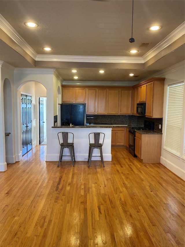 1711 Aden Mist Dr, Houston, TX 77003 - kitchen featuring black appliances, crown molding, a raised ceiling, arched walkways, and tasteful backsplash