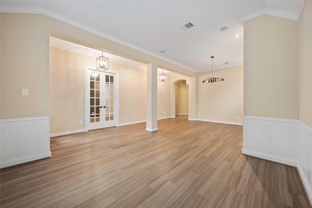 13721 Northline Lake Dr, Houston, TX 77044 - empty room featuring arched walkways, ornamental molding, light wood-type flooring, french doors, and a wainscoted wall
