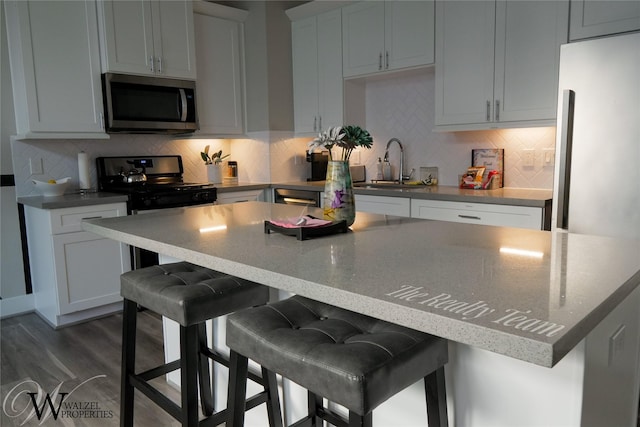 5902 Gardendale Dr Unit C, Houston, TX 77092 - kitchen with stainless steel microwave, a kitchen island, black gas range, decorative backsplash, and a breakfast bar area