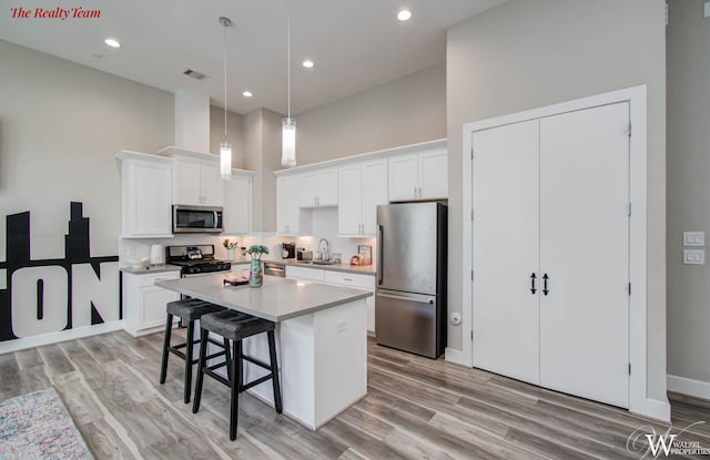 5902 Gardendale Dr Unit C, Houston, TX 77092 - kitchen with appliances with stainless steel finishes, a kitchen island, a kitchen bar, white cabinetry, and a high ceiling