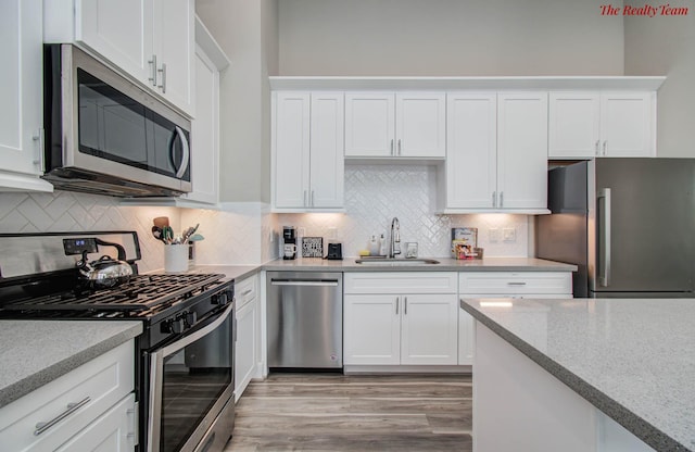 5902 Gardendale Dr Unit C, Houston, TX 77092 - kitchen with stainless steel appliances, white cabinetry, light wood-style flooring, and backsplash