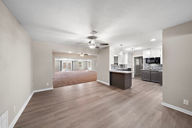 1033 25th Ave N, Texas City, TX 77590 - kitchen with black microwave, ceiling fan, open floor plan, white cabinetry, and decorative backsplash