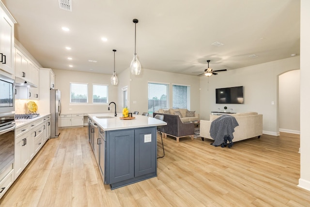 9806 Starry Night Ln, Manvel, TX 77578 - kitchen with arched walkways, light wood-style flooring, appliances with stainless steel finishes, open floor plan, and light countertops