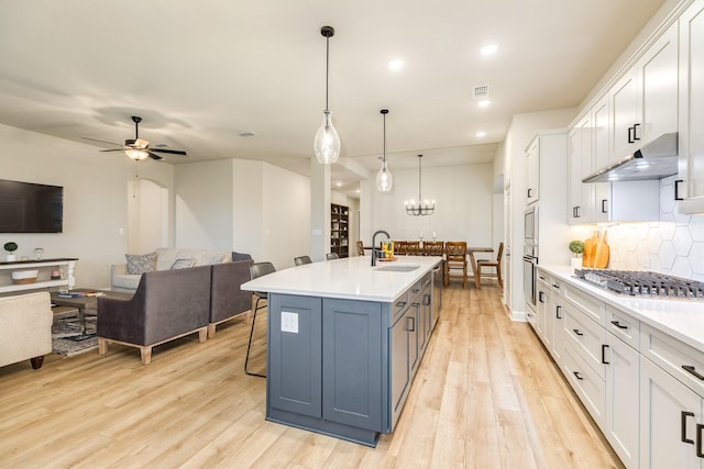 9806 Starry Night Ln, Manvel, TX 77578 - kitchen with stainless steel gas cooktop, under cabinet range hood, backsplash, light countertops, and recessed lighting