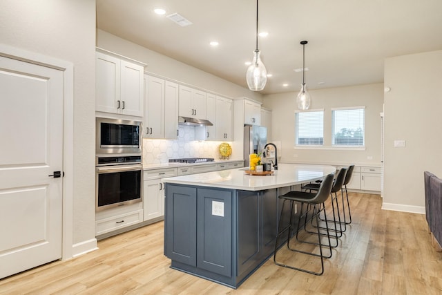 9806 Starry Night Ln, Manvel, TX 77578 - kitchen featuring appliances with stainless steel finishes, under cabinet range hood, light wood-style floors, decorative backsplash, and recessed lighting