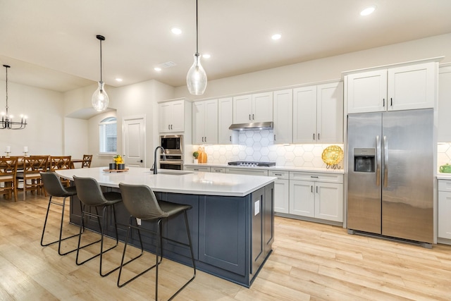 9806 Starry Night Ln, Manvel, TX 77578 - kitchen with stainless steel appliances, backsplash, light countertops, white cabinetry, and light wood-type flooring