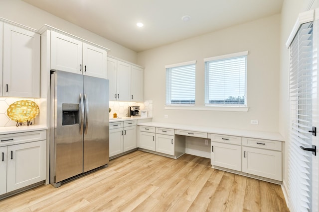 9806 Starry Night Ln, Manvel, TX 77578 - kitchen with stainless steel fridge, decorative backsplash, light countertops, white cabinetry, and light wood-style floors