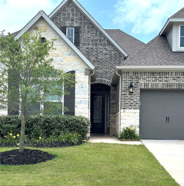 9806 Starry Night Ln, Manvel, TX 77578 - french country home with stone siding, an attached garage, a shingled roof, and a front lawn
