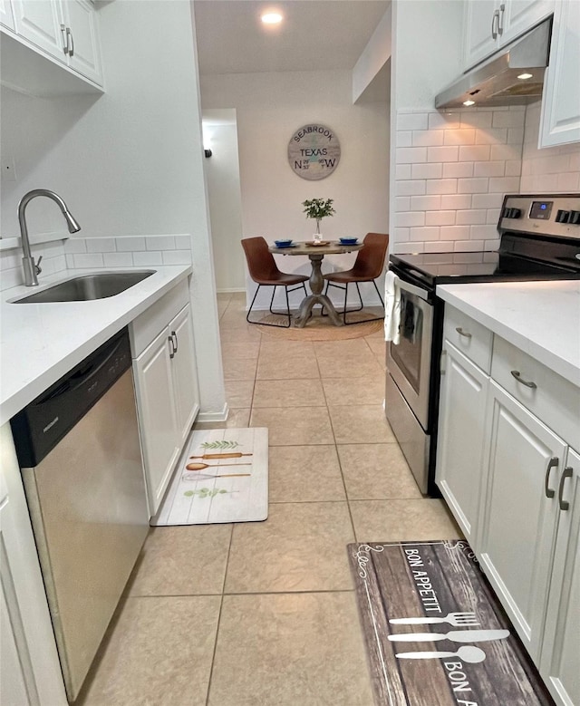 3300 Pebblebrook Dr Unit 17, Seabrook, TX 77586 - kitchen with appliances with stainless steel finishes, under cabinet range hood, backsplash, light countertops, and white cabinets