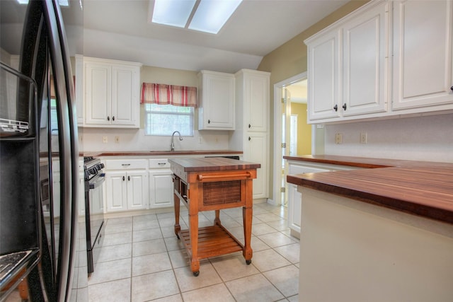 2115 Greentree Dr, Huntsville, TX 77340 - kitchen featuring butcher block counters, black appliances, white cabinets, light tile patterned floors, and vaulted ceiling