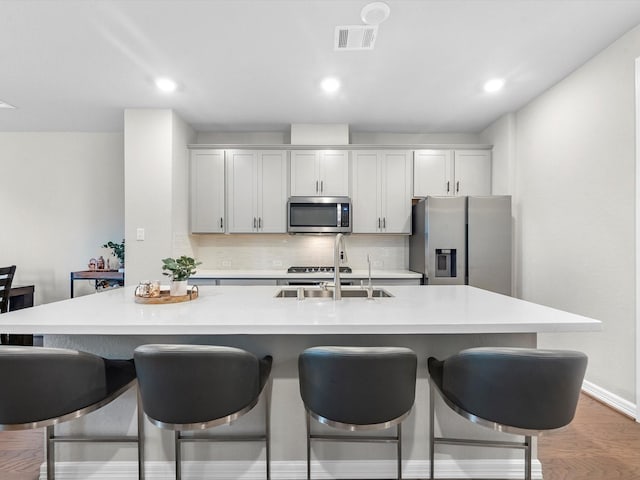 9440 Caddo Ridge Ln, Cypress, TX 77433 - kitchen with stainless steel appliances, tasteful backsplash, a breakfast bar, a center island with sink, and light countertops