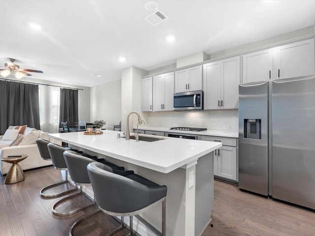 9440 Caddo Ridge Ln, Cypress, TX 77433 - kitchen with appliances with stainless steel finishes, a kitchen breakfast bar, an island with sink, decorative backsplash, and open floor plan