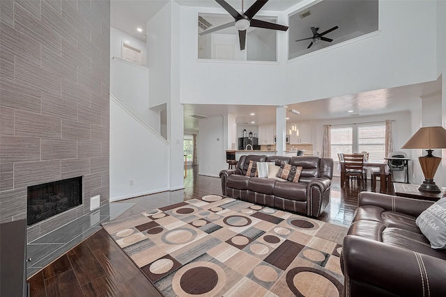 14212 Rocky Briar Ln, Rosharon, TX 77583 - living room featuring a ceiling fan, a high ceiling, wood finished floors, a tile fireplace, and decorative columns