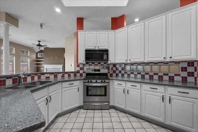 110 Crimson Bay Dr, League City, TX 77573 - kitchen with black microwave, stainless steel range with gas stovetop, a ceiling fan, white cabinets, and backsplash