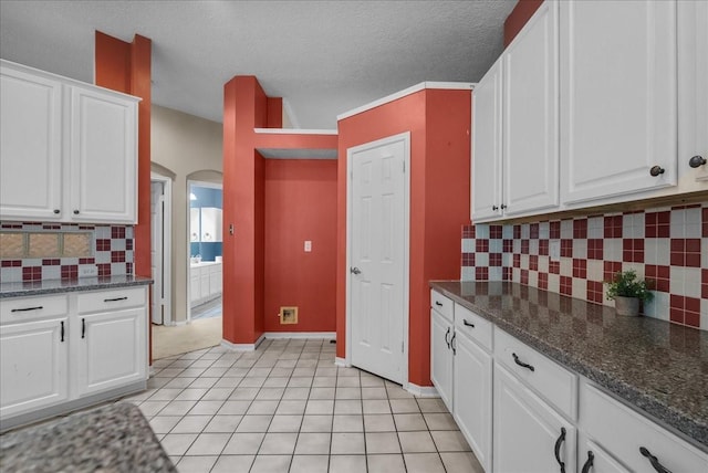 110 Crimson Bay Dr, League City, TX 77573 - kitchen with arched walkways, white cabinetry, tasteful backsplash, light tile patterned floors, and a textured ceiling