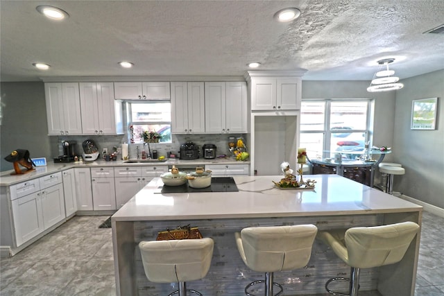 15902 Seven Springs Dr, Houston, TX 77084 - kitchen with white cabinets, black electric cooktop, tasteful backsplash, light countertops, and recessed lighting