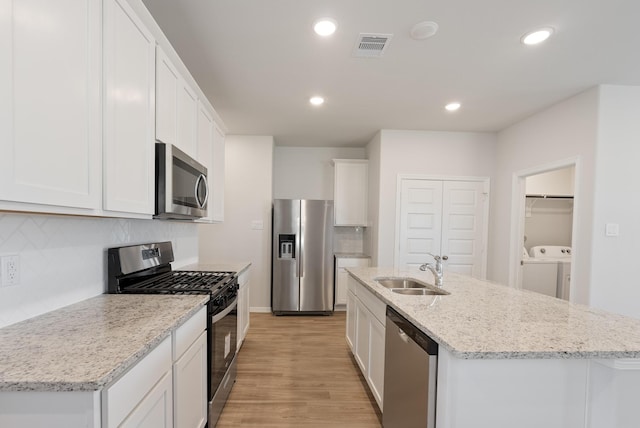 5827 Fresh View Ct, Katy, TX 77493 - kitchen featuring appliances with stainless steel finishes, washing machine and clothes dryer, light wood-style flooring, backsplash, and white cabinetry