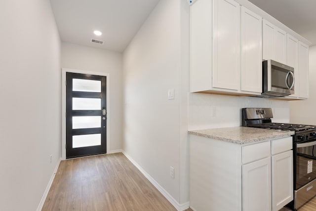 5827 Fresh View Ct, Katy, TX 77493 - kitchen with appliances with stainless steel finishes, light wood-style flooring, white cabinets, and light stone counters