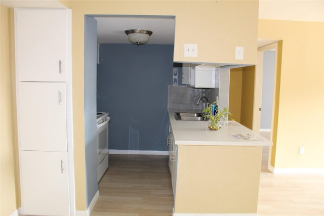6161 Reims Rd Unit 611, Houston, TX 77036 - kitchen with light wood-type flooring, white electric stove, backsplash, and light countertops