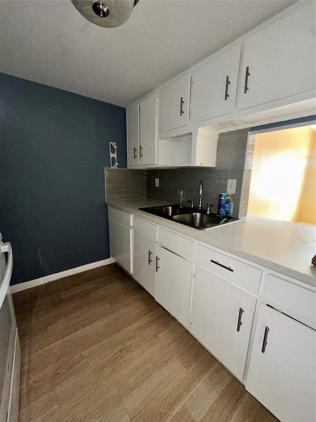 6161 Reims Rd Unit 611, Houston, TX 77036 - kitchen with light wood-style flooring, decorative backsplash, white cabinetry, and light countertops