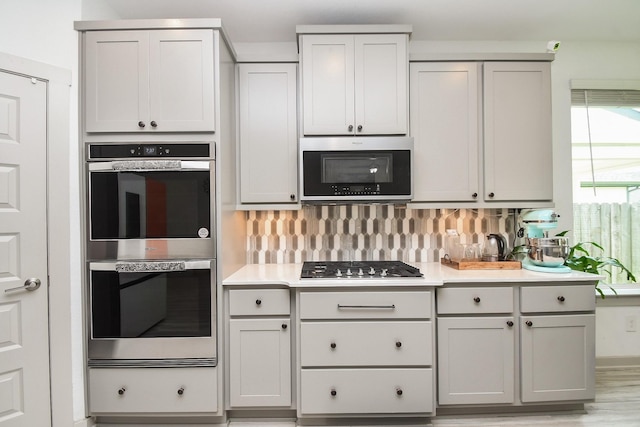 3819 Ethan Park Ct, Katy, TX 77494 - kitchen with appliances with stainless steel finishes, gray cabinetry, tasteful backsplash, and light countertops