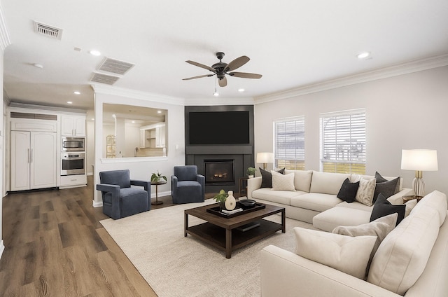 12014 Via Davinci Ln NW, Cypress, TX 77429 - living room with a ceiling fan, dark wood-type flooring, recessed lighting, crown molding, and a glass covered fireplace